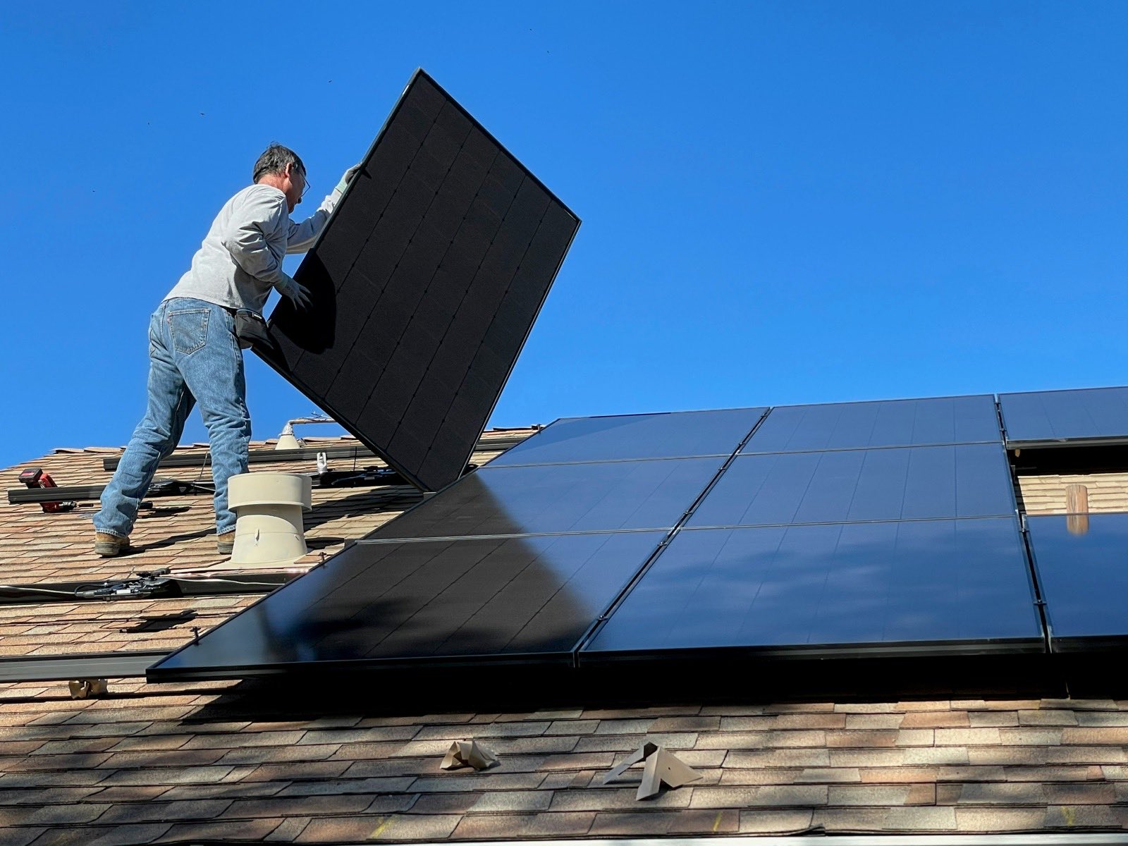 person installing a solar panel on a roof