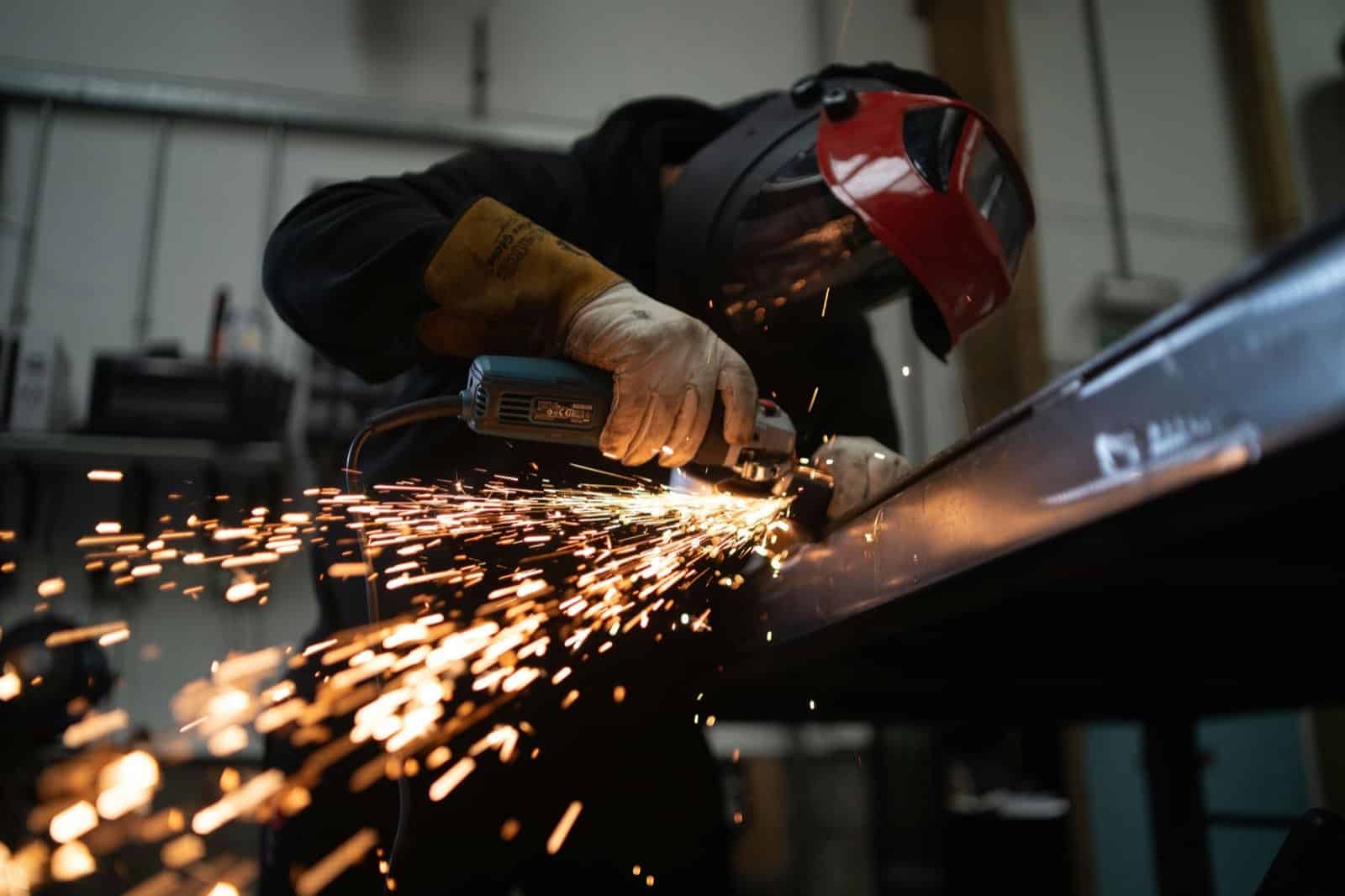 tXJhAFVOHVk-unsplash welding helmet, grinding a metal beam with sparks