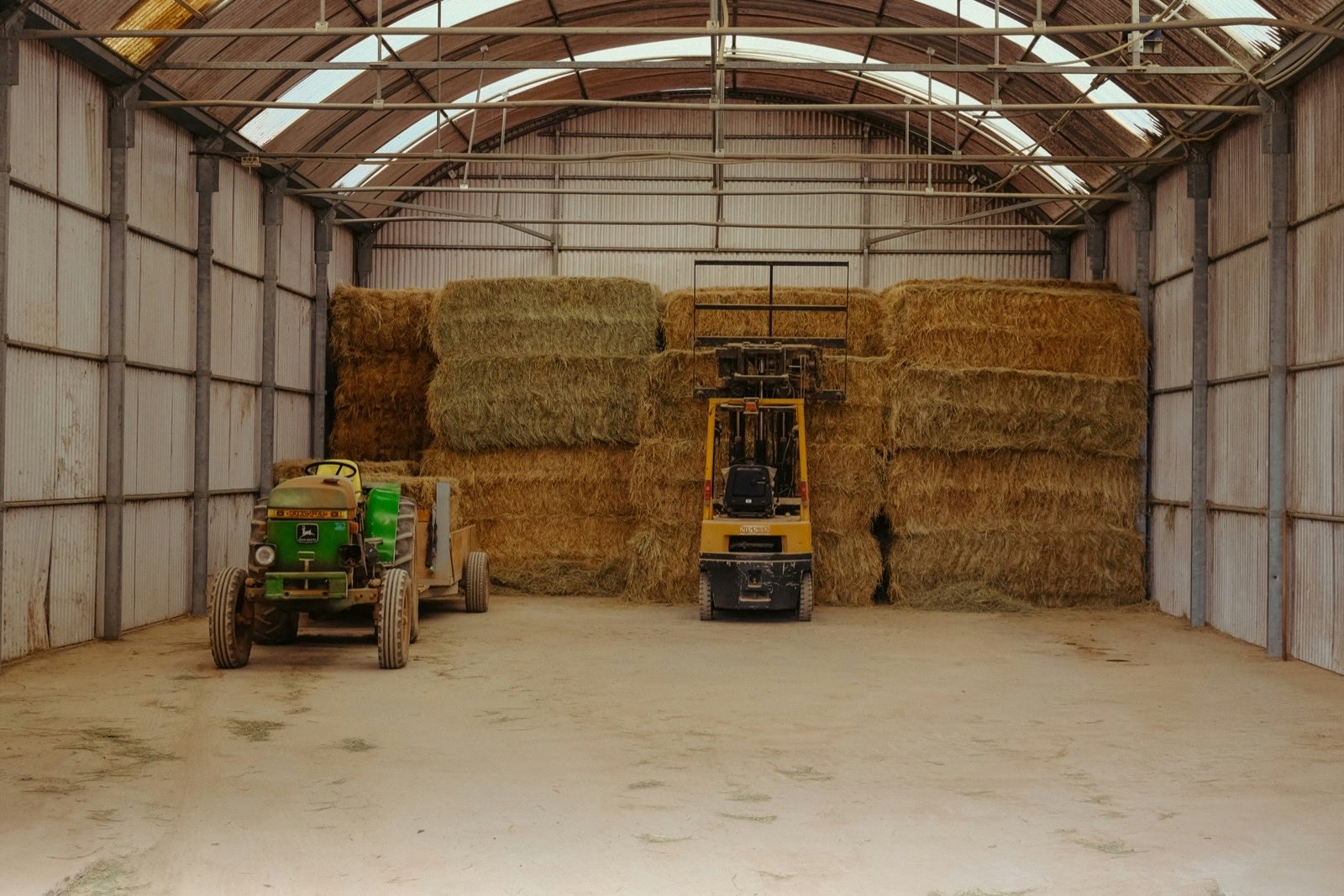 a warehouse with hay bales and a tractor