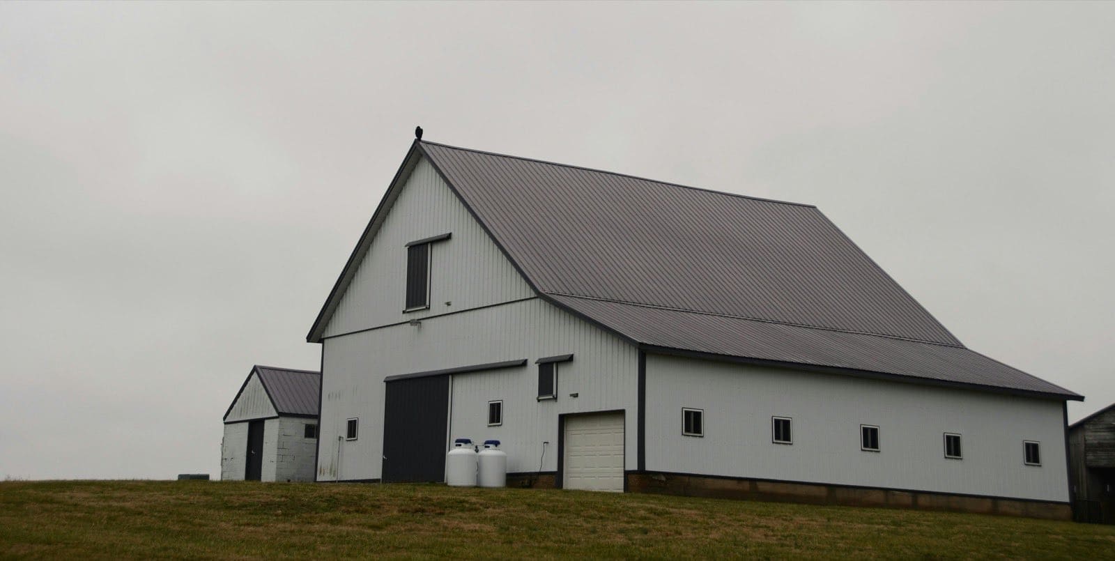 a white barn on a grassy hill